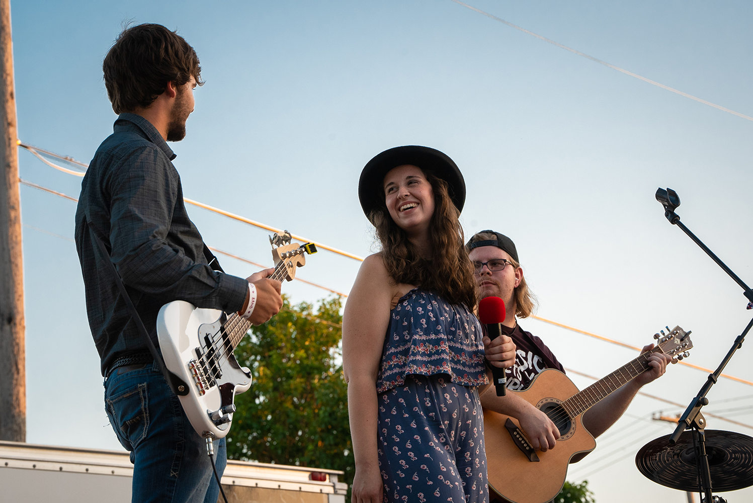 Three young musicians stand smiling.